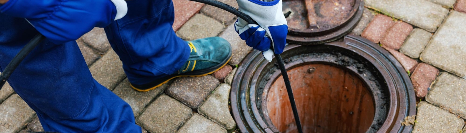 Worker using hydro jet system to clean pipes